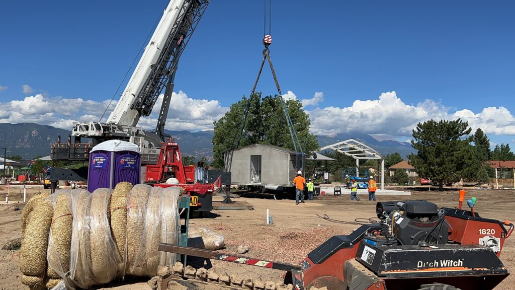 Wide photograph of the bathroom being lowered into the park from a crane