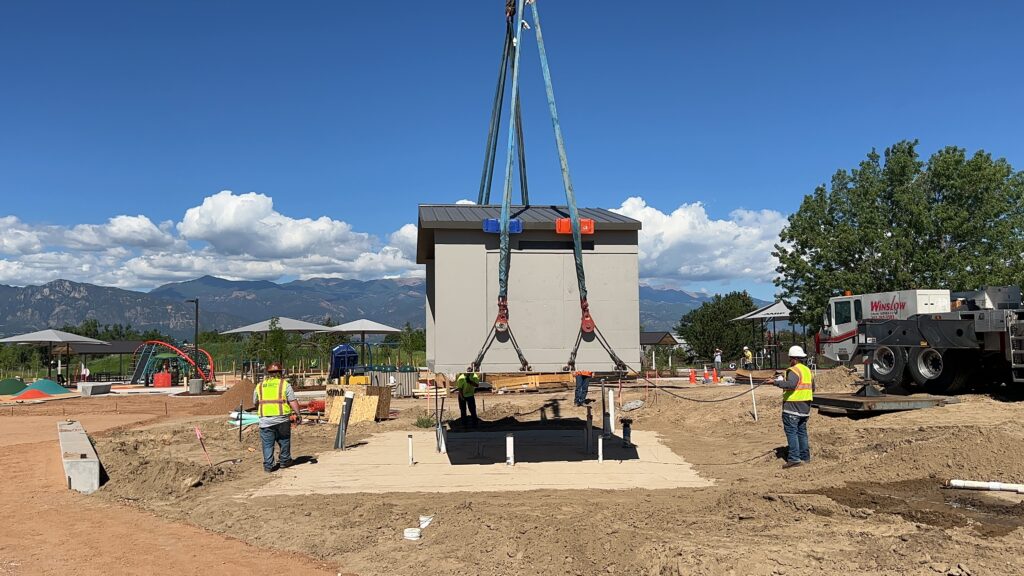 A photo of a crane lowering a bathroom into the park